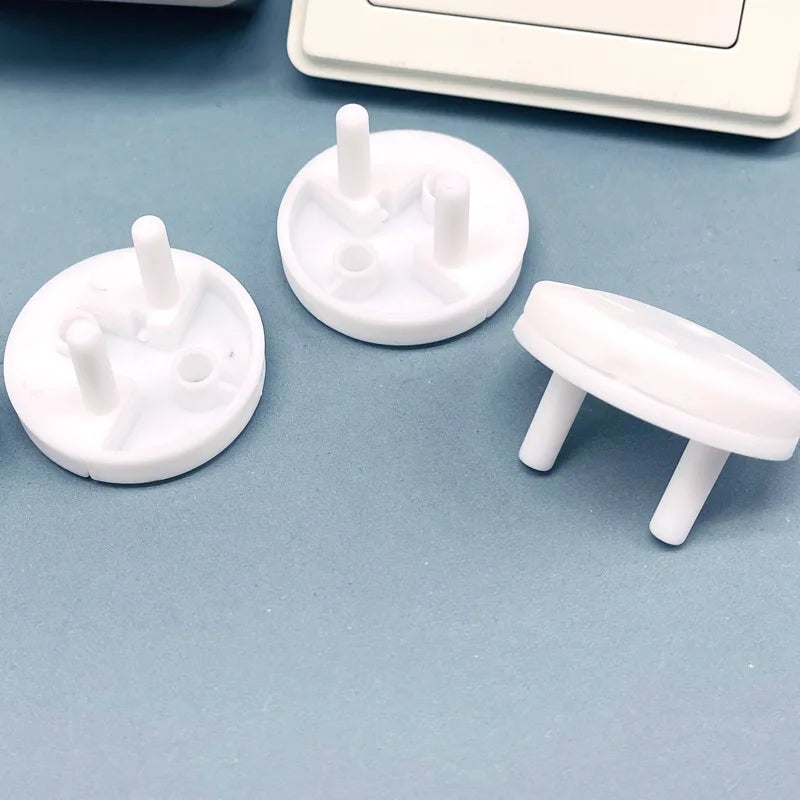 Gros plan sur cache-prises de sécurité enfant avec système rotatif, montrant les picots de fixation et le mécanisme anti-retrait